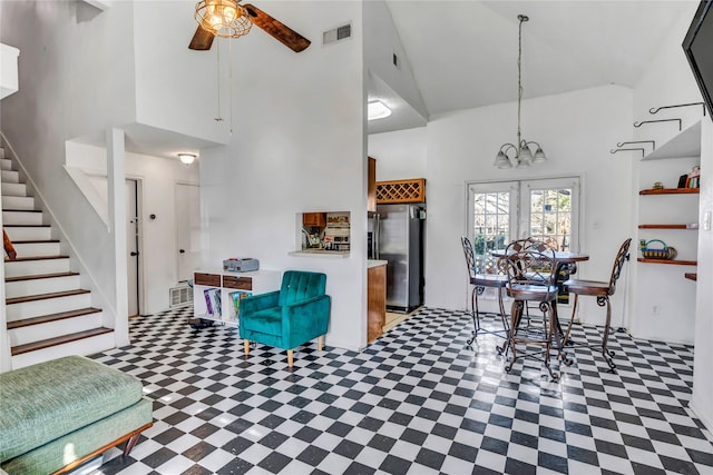 living room featuring a towering ceiling and ceiling fan with notable chandelier