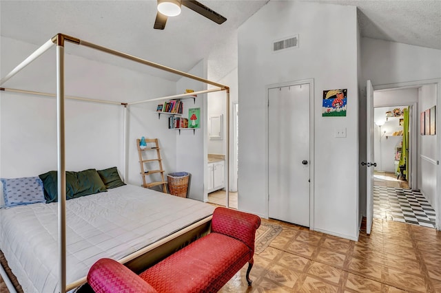 bedroom with lofted ceiling, ensuite bathroom, a textured ceiling, ceiling fan, and light parquet floors