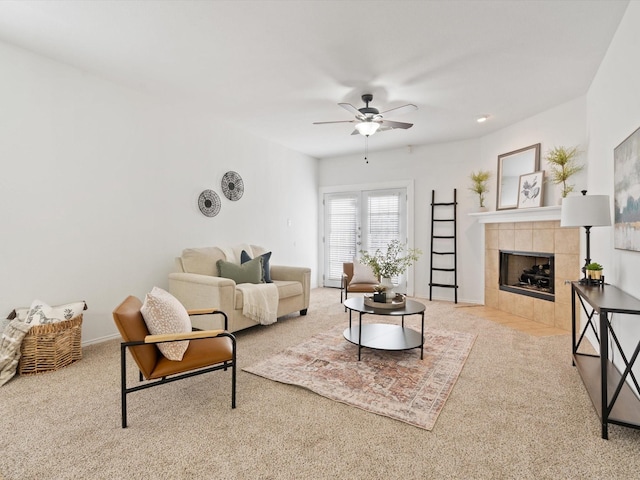 living area featuring ceiling fan, baseboards, carpet flooring, and a tile fireplace