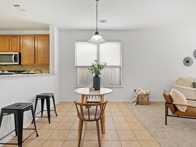 dining space featuring light tile patterned floors, baseboards, and visible vents