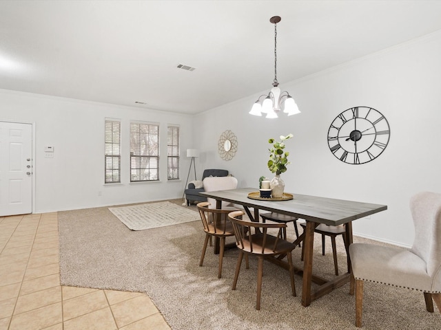 dining area with light tile patterned flooring, ornamental molding, and a notable chandelier