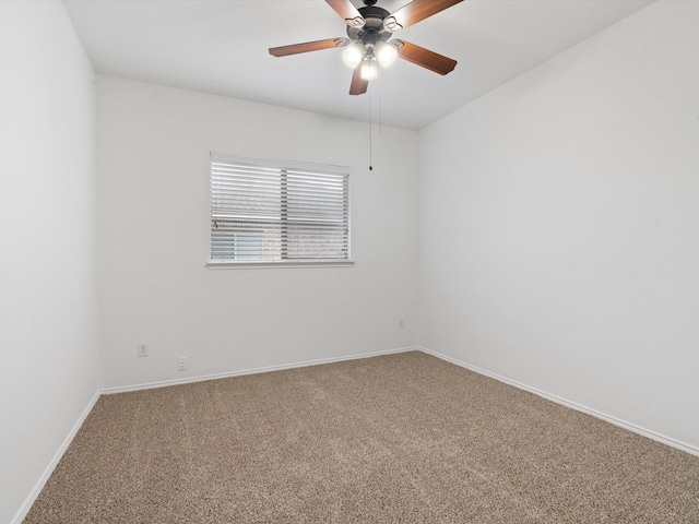 carpeted spare room featuring baseboards and a ceiling fan