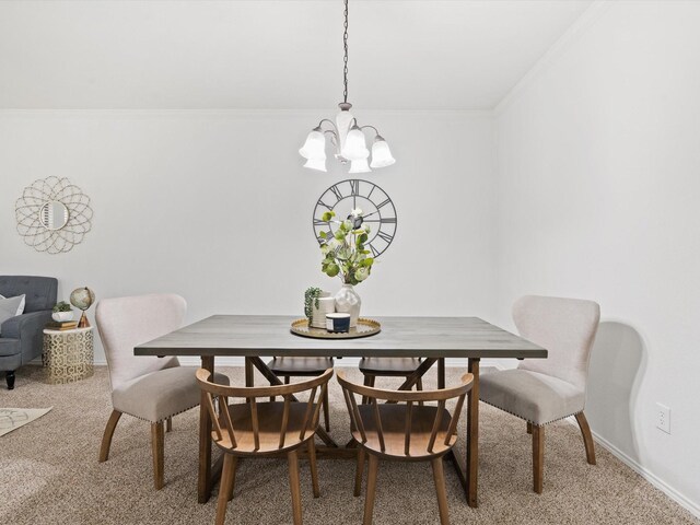 dining space featuring light carpet, ornamental molding, a chandelier, and baseboards