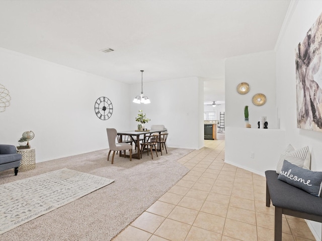 dining area featuring light tile patterned flooring, ceiling fan with notable chandelier, visible vents, and light colored carpet