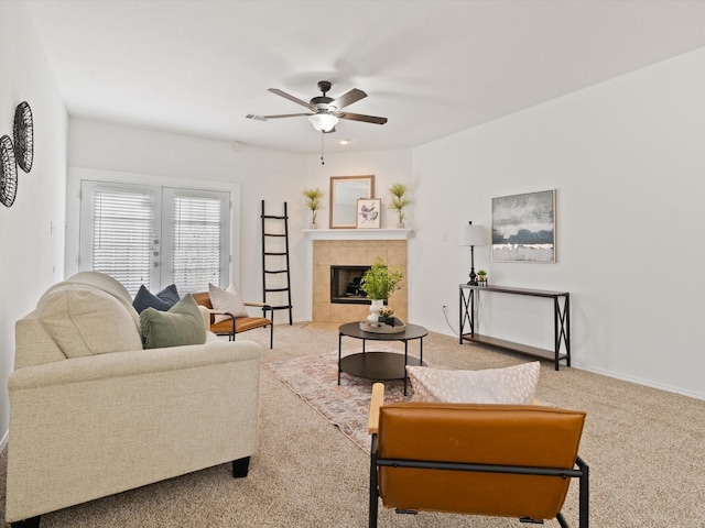 carpeted living area with baseboards, ceiling fan, and a tiled fireplace