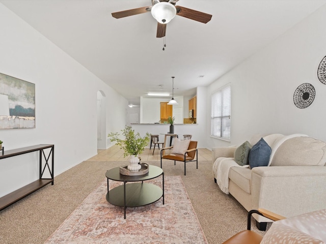 living room featuring ceiling fan, arched walkways, and light colored carpet