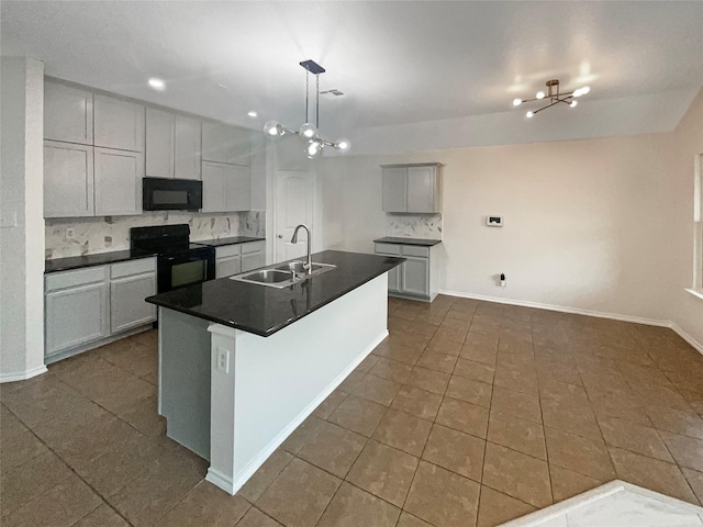 kitchen featuring sink, gray cabinetry, a kitchen island with sink, black appliances, and an inviting chandelier