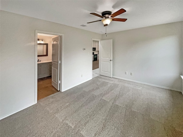 unfurnished bedroom featuring light carpet, connected bathroom, and ceiling fan