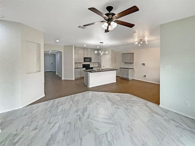 kitchen featuring pendant lighting, sink, stove, a kitchen island with sink, and ceiling fan