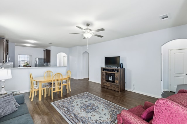 living room featuring dark wood-type flooring and ceiling fan