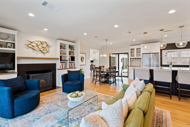 living room featuring a tiled fireplace, a wealth of natural light, and light hardwood / wood-style flooring