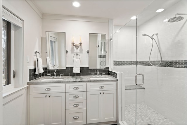 bathroom with crown molding, vanity, a shower with shower door, and decorative backsplash