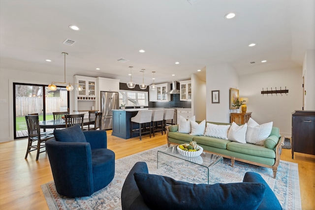 living room with lofted ceiling, sink, and light hardwood / wood-style floors