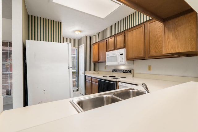 kitchen with sink, white appliances, and kitchen peninsula