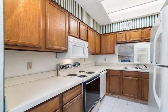 kitchen featuring white appliances, sink, and light tile patterned floors