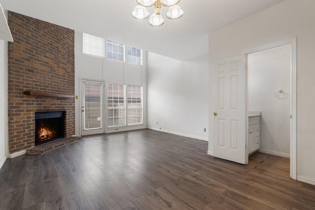 unfurnished living room with a fireplace, dark wood-type flooring, and a chandelier