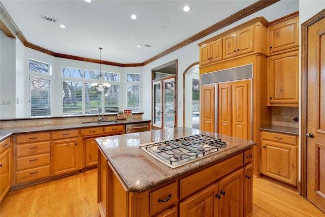 kitchen with pendant lighting, sink, appliances with stainless steel finishes, a center island, and light hardwood / wood-style floors