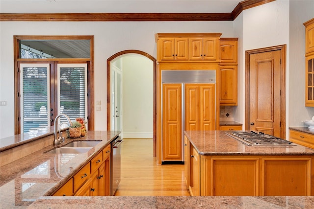 kitchen featuring sink, paneled refrigerator, ornamental molding, stainless steel gas stovetop, and light hardwood / wood-style floors