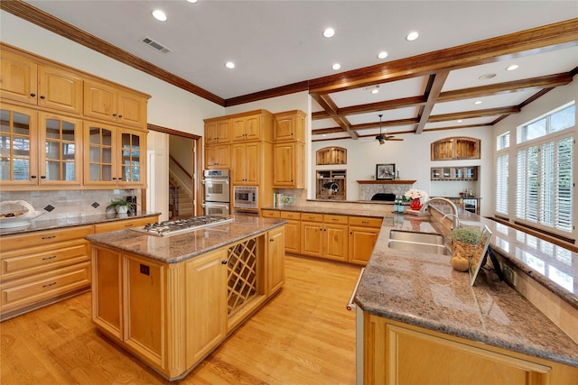 kitchen with sink, coffered ceiling, stainless steel appliances, light wood-type flooring, and a spacious island