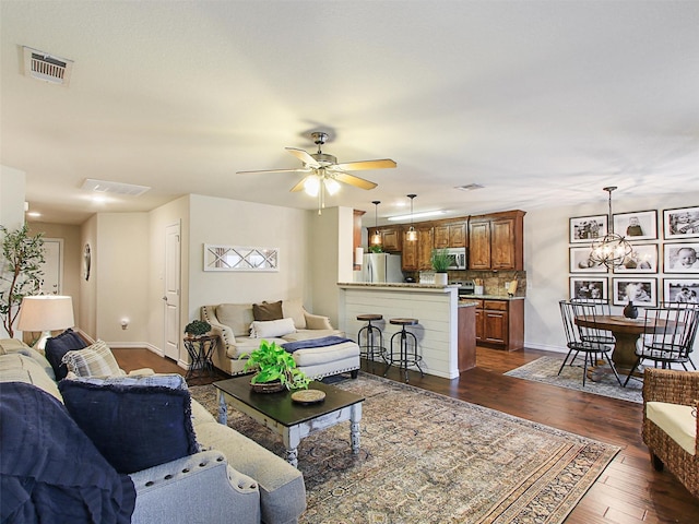 living room with dark wood-type flooring and ceiling fan with notable chandelier