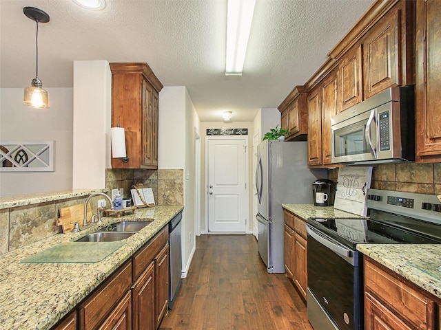 kitchen featuring dark hardwood / wood-style floors, decorative light fixtures, sink, light stone counters, and stainless steel appliances