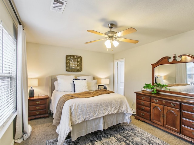 carpeted bedroom featuring multiple windows and ceiling fan