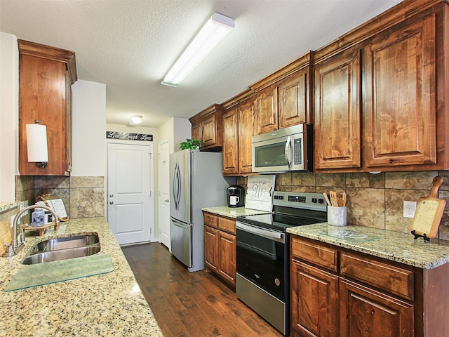 kitchen with light stone counters, sink, and stainless steel appliances