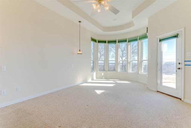 carpeted spare room featuring ceiling fan and a tray ceiling