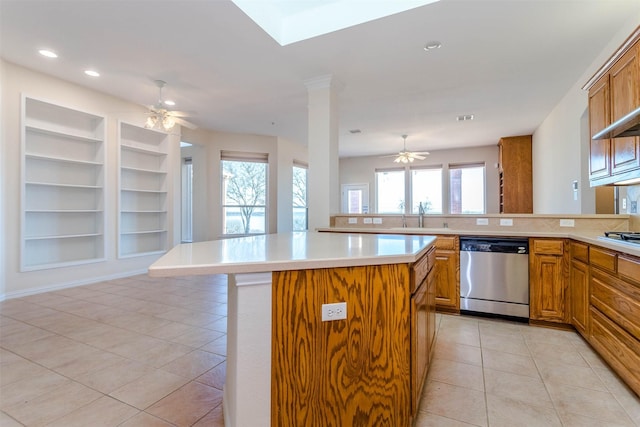 kitchen with light tile patterned flooring, built in shelves, a center island, stainless steel dishwasher, and ceiling fan