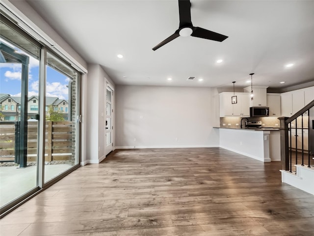 unfurnished living room with sink, hardwood / wood-style floors, and ceiling fan