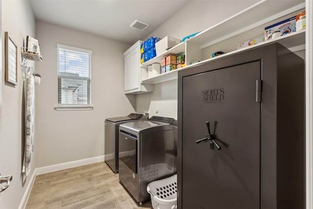 washroom with cabinets, washing machine and clothes dryer, and light wood-type flooring