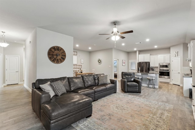 living room with ceiling fan and light wood-type flooring