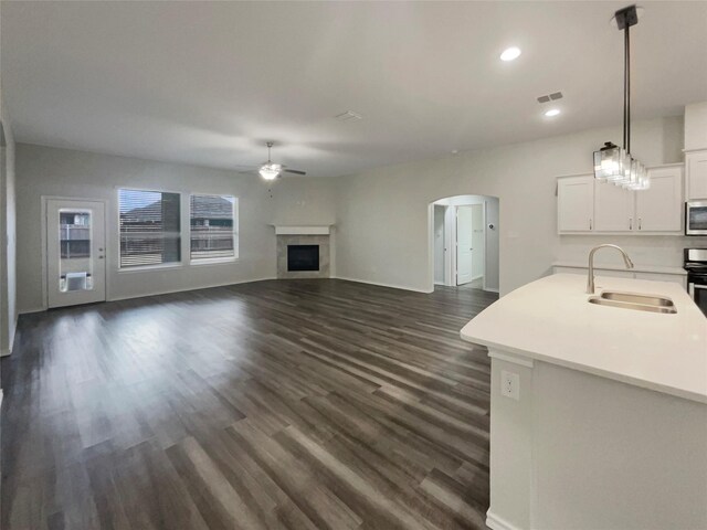 unfurnished living room featuring dark hardwood / wood-style flooring, sink, and ceiling fan