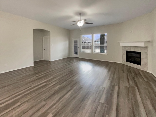 unfurnished living room featuring dark wood-type flooring, ceiling fan, and a fireplace