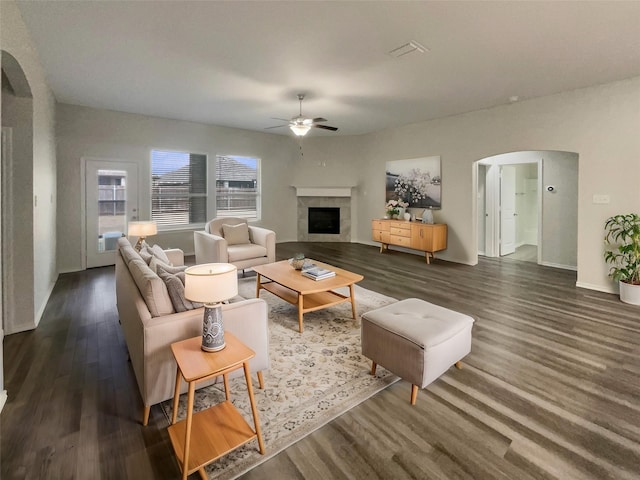 living room featuring a tile fireplace, dark hardwood / wood-style floors, and ceiling fan