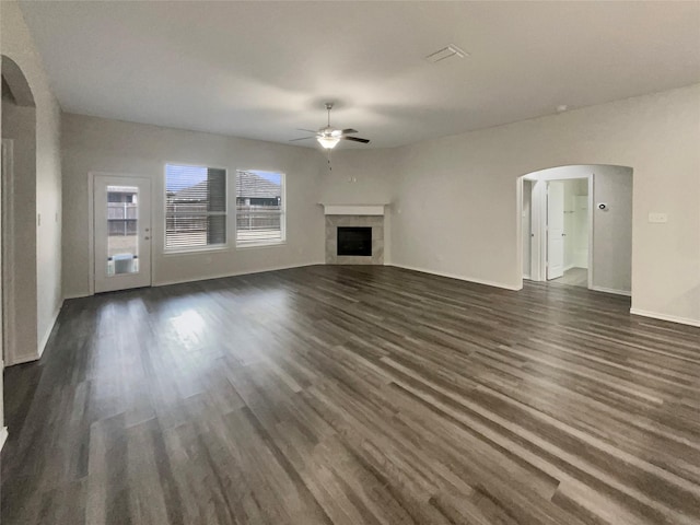 unfurnished living room with a tile fireplace, dark hardwood / wood-style flooring, and ceiling fan