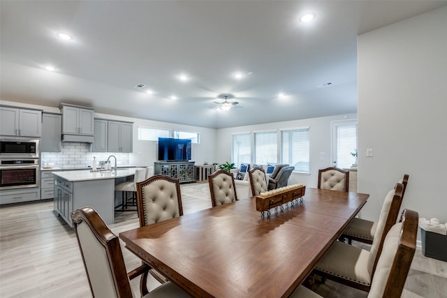 dining room featuring ceiling fan, a healthy amount of sunlight, sink, and light hardwood / wood-style floors