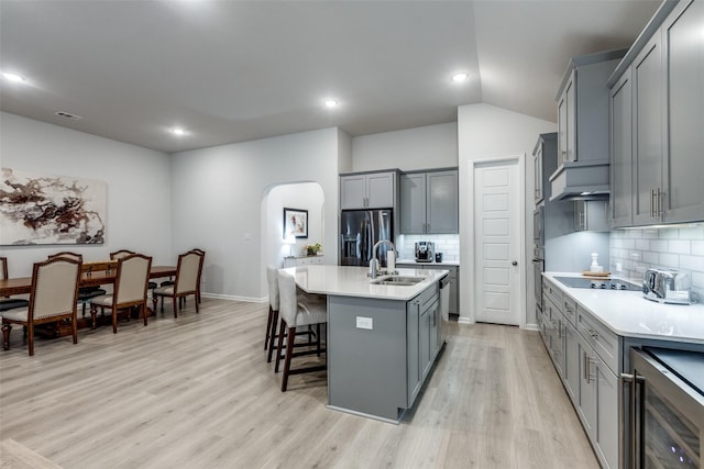 kitchen featuring wine cooler, a breakfast bar, sink, stainless steel fridge with ice dispenser, and a center island with sink