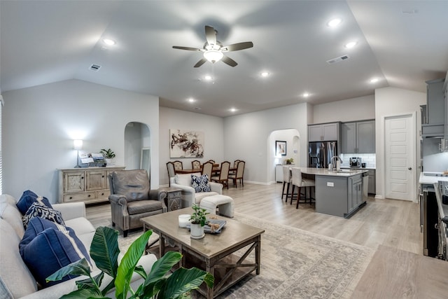 living room with ceiling fan, sink, vaulted ceiling, and light hardwood / wood-style flooring