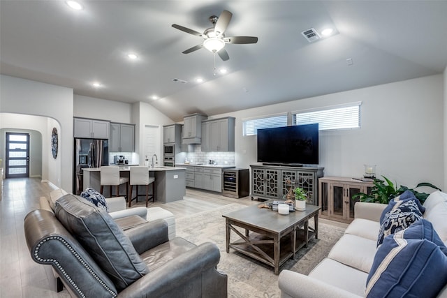 living room with vaulted ceiling, sink, wine cooler, ceiling fan, and light hardwood / wood-style flooring