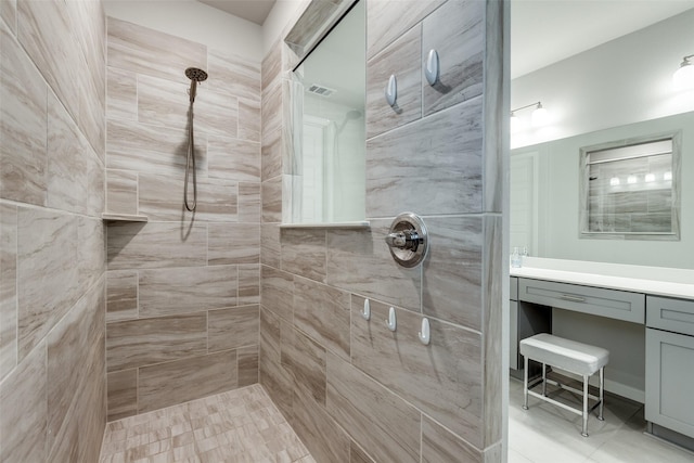 bathroom with a tile shower and vanity