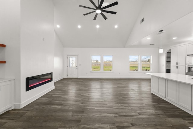 unfurnished living room with ceiling fan, dark hardwood / wood-style flooring, and high vaulted ceiling