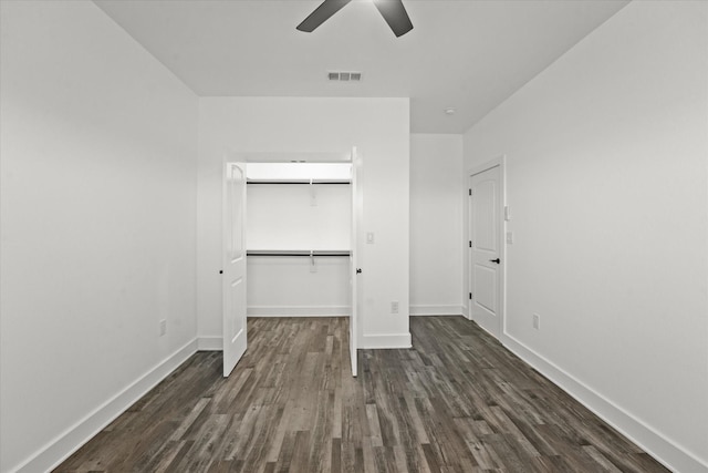 unfurnished bedroom with a closet, a spacious closet, dark hardwood / wood-style floors, and ceiling fan