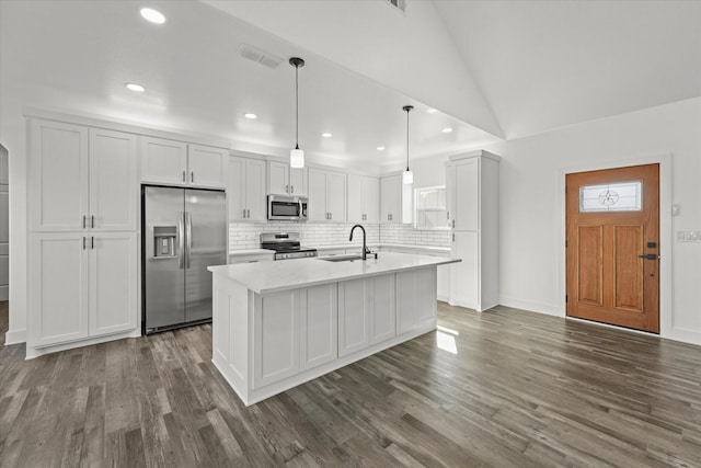 kitchen with sink, appliances with stainless steel finishes, an island with sink, pendant lighting, and white cabinets