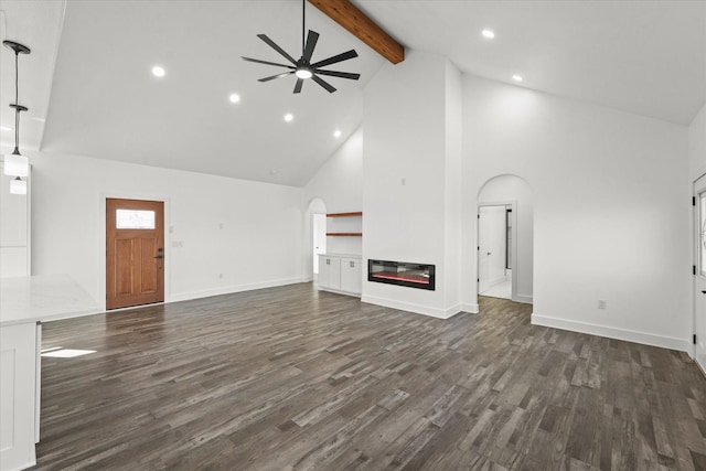 unfurnished living room with ceiling fan, high vaulted ceiling, dark hardwood / wood-style floors, and beam ceiling