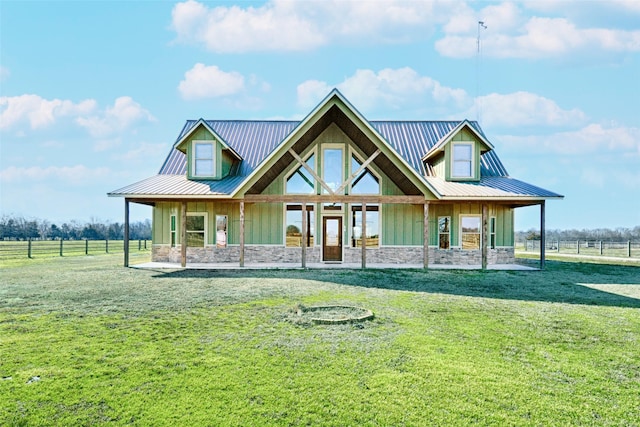 view of front of house featuring stone siding, a front lawn, metal roof, and board and batten siding