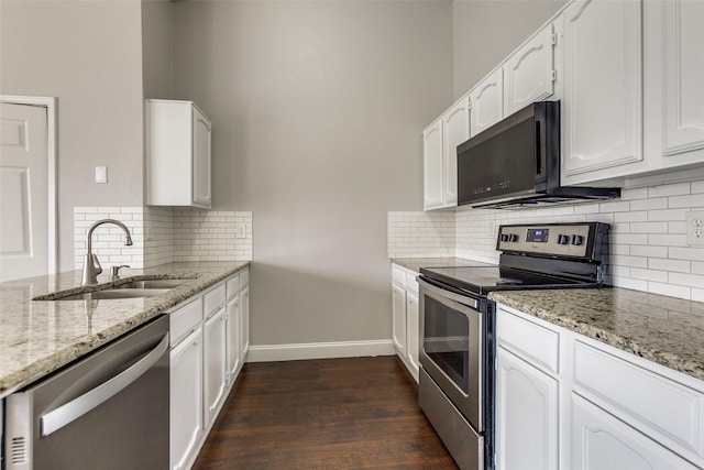 kitchen with sink, dark hardwood / wood-style flooring, stainless steel appliances, light stone countertops, and white cabinets