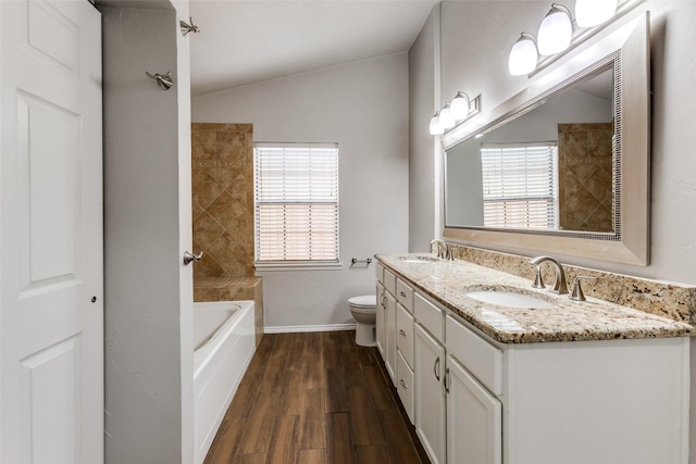 bathroom featuring hardwood / wood-style flooring, vanity, vaulted ceiling, and toilet