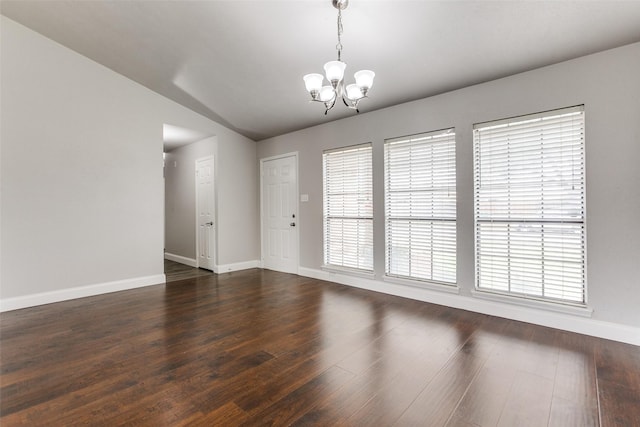 empty room featuring dark hardwood / wood-style flooring, a wealth of natural light, and a chandelier