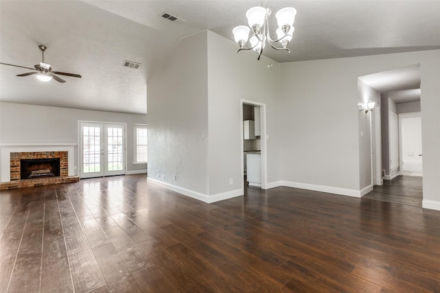 unfurnished living room with french doors, dark hardwood / wood-style flooring, ceiling fan with notable chandelier, and a brick fireplace